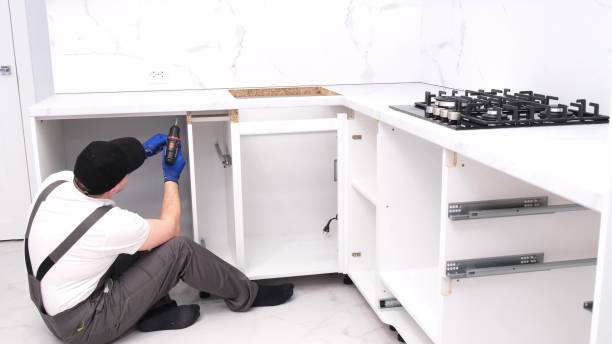 istock A craftsman in a black cap assembles furniture in the kitchen 2000784698