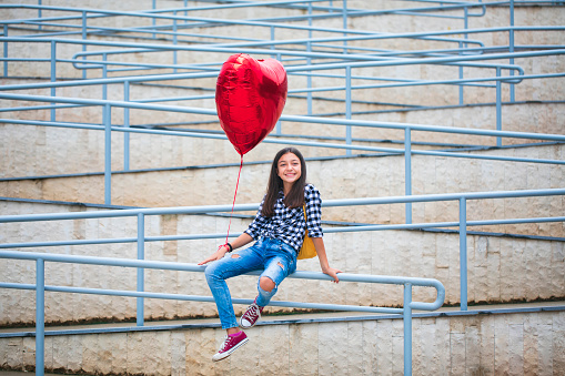 Portrait of a beautiful smiling girl with heart shape balloon. Love concept.