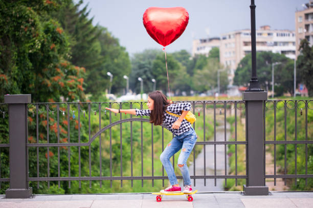 istock Girl with skateboard and heart shape balloon 2000789499