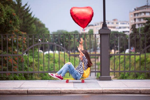 istock Girl with skateboard and heart shape balloon 2000790038
