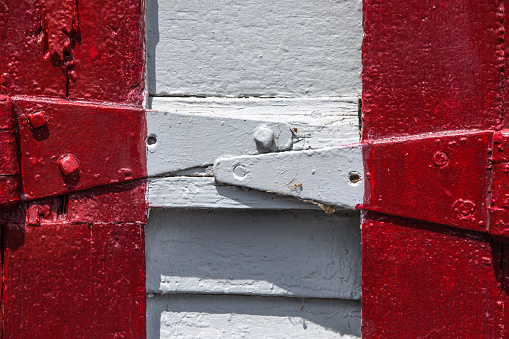 Barn hinges painted in alternating colors of white and red, add a touch of rustic charm to the weathered structure.