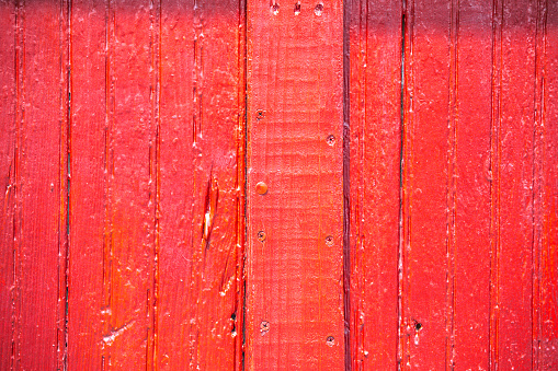 A wooden barn exterior wall is painted red provides a rustic background.