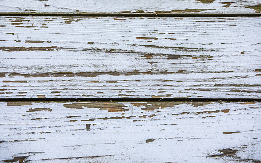 Close-up of three wooden planks with chipped and peeling white paint works as a rustic background.