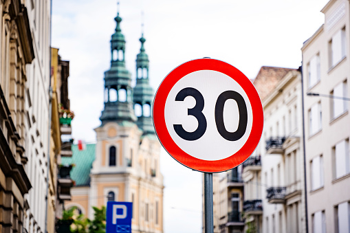 Car speed limit sign at street of old city center. Warning for traffic regulation