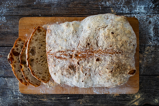 Loaf of homemade, fresh bread with sunflower seeds and linseed on wooden background