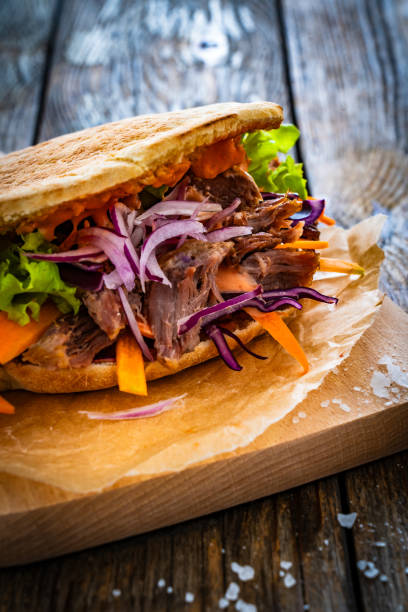istock Pita - big sandwich with pulled beef and fresh vegetables on wooden table 2000909813