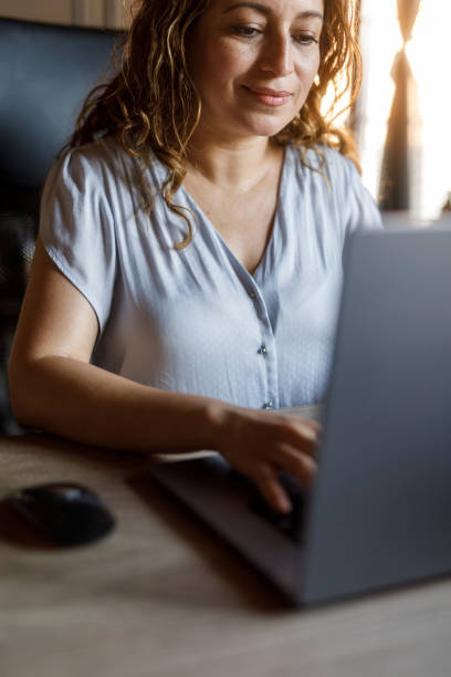 istock Woman sitting at her desk, using laptop when working 2000992110