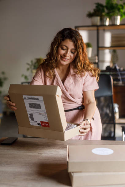 istock Woman opening a cardboard box to pack customer's order 2000994754