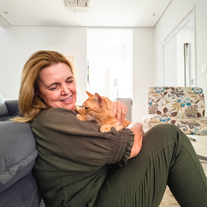 Photo of a mature woman and his ginger cat at home.