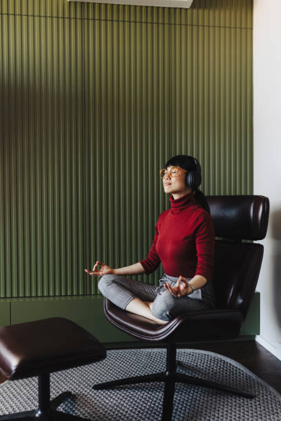 donna che medita e ascolta musica a casa - yoga business women living room foto e immagini stock