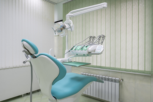 The dental office features a modern dental chair situated in the building's interior, surrounded by walls adorned with aqua art. The ceiling above complements the soothing water-themed decor.