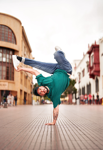 latin American breakdancer guy performing inverted freeze V technique on the street