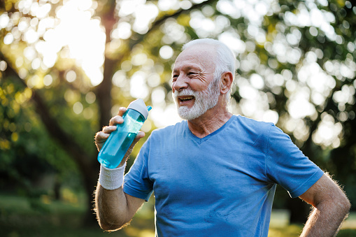 Sporty senior man drinking water outdoors