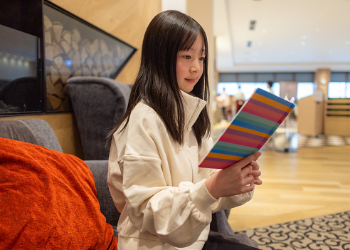 Teenage girl reading book in the hotel lobby