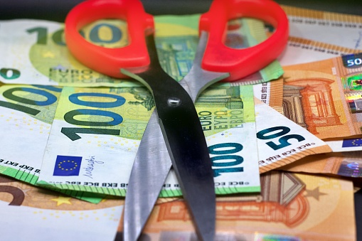 Business concept, Euro banknote is cut with scissors, symbol for wage reduction or pay less money, selected focus