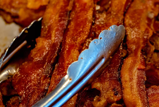 Roasted bacon slices on a brown background. Roasted bacon on a fork.