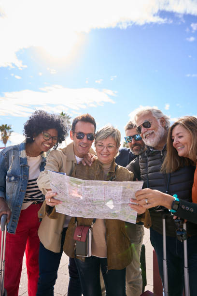istock Group diverse middle-aged tourist people standing looking at travel map in hands on vacation city. 2001148765