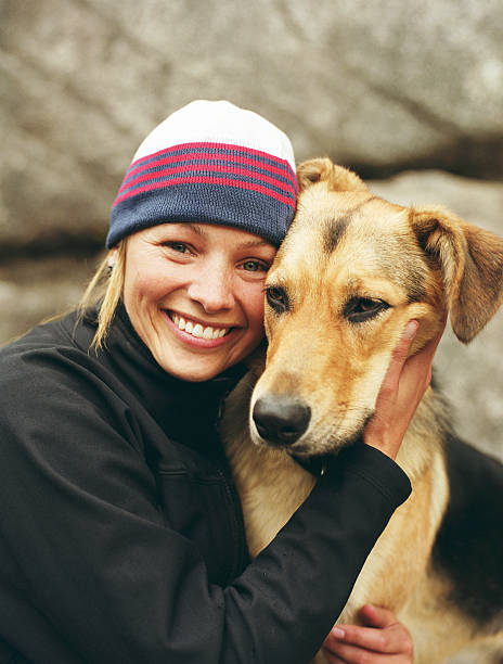 woman wearing knit cap, hugging dog, portrait - pets embracing one person portrait - fotografias e filmes do acervo