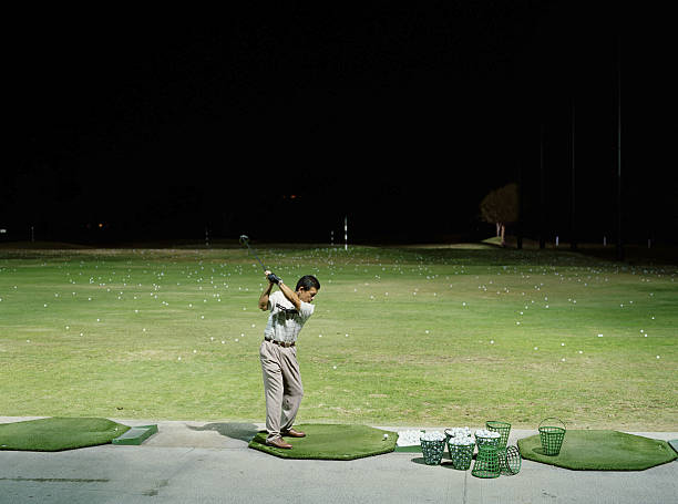 Man practicing golf on  driving range at night  night golf stock pictures, royalty-free photos & images