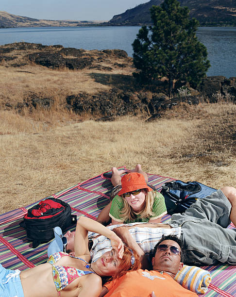 4 つの若い大人の川のそばで日光浴ブランケット - swimming trunks bikini swimwear red ストックフォトと画像