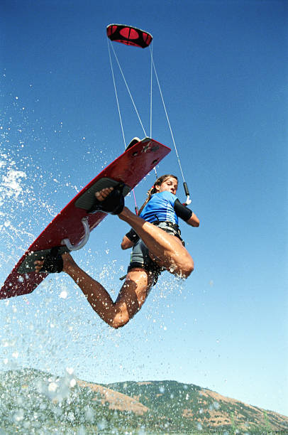 kiteboarder femminile in mid-air, guardare indietro, basso angolo - on top of activity adult adventure foto e immagini stock