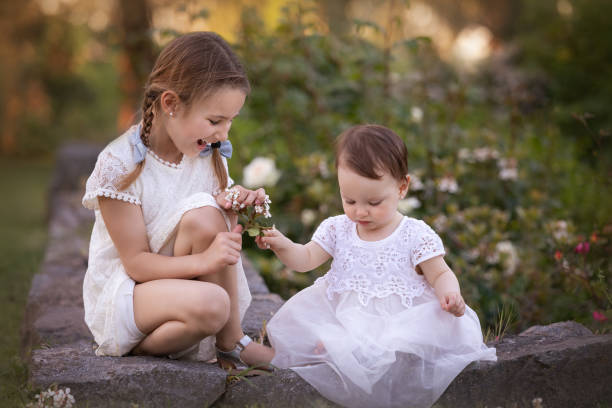 Cute little girl smells an iris flower in the yard during spring day