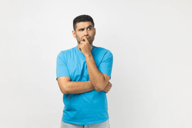 istock Serious thoughtful unshaven man standing keeps hand on his chin, thinking about work, looking away. 2001252240
