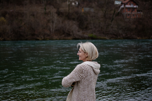 mature blonde woman is in nature next to a clear mountain river on the weekend