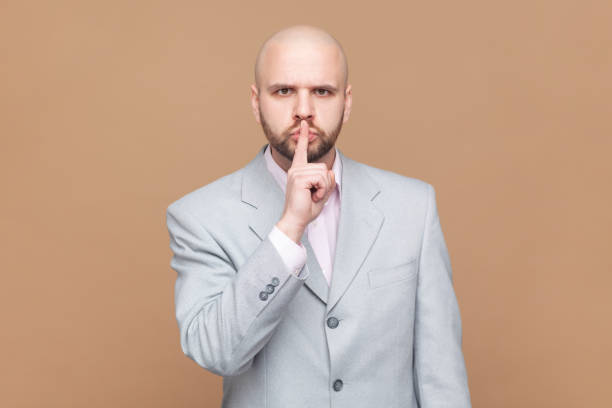 istock Man makes silence or hush gesture, keep index fingers over lips, tells secret information to someone 2001284668