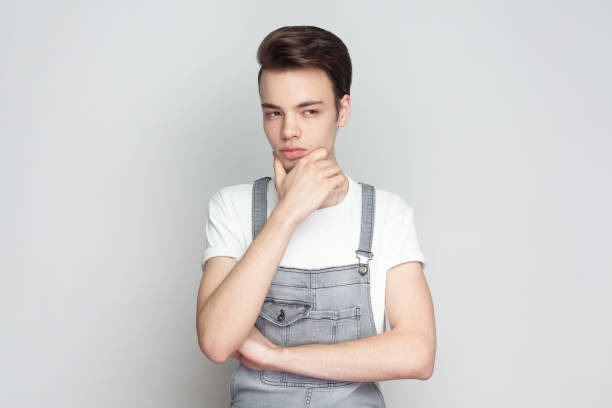 istock Man holding chin and looks confused somewhere, thinks how to solve clue, has pensive expression. 2001284690
