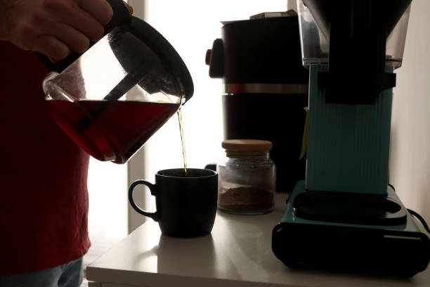 istock Man pours freshly brewed coffee into his glass in the kitchen 2001286890