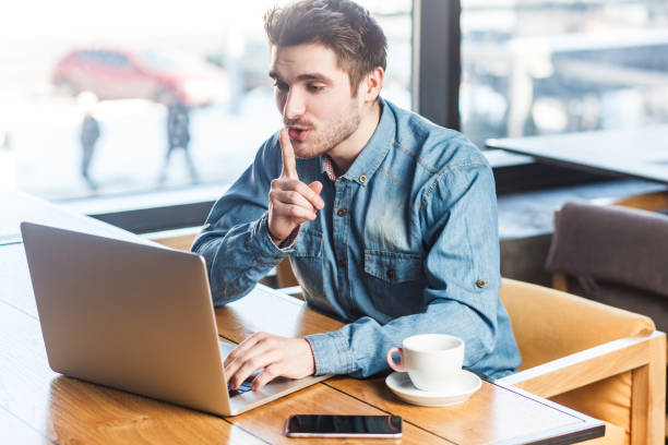 istock Attractive man freelancer working on laptop, having video call, showing silent gesture. 2001286905
