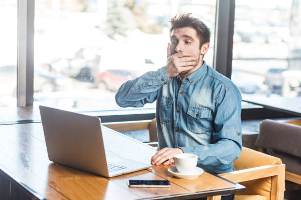 istock Handsome shocked scared man freelancer working on laptop, looking at screen covering mouth with palm 2001286907