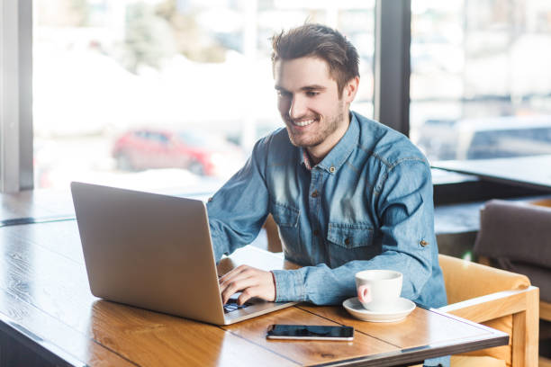 istock Smiling happy satisfied man freelancer working on laptop, typing on keyboard, having video call. 2001286909