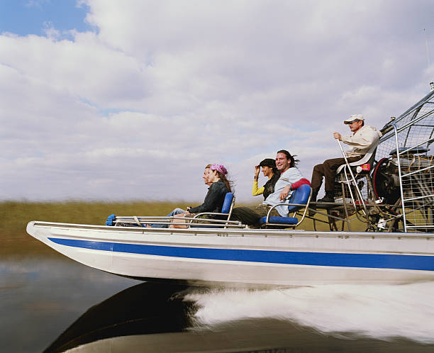 Driver and four passengers on airboat, side view Everglades Safari Park, Florida, USA everglades national park photos stock pictures, royalty-free photos & images