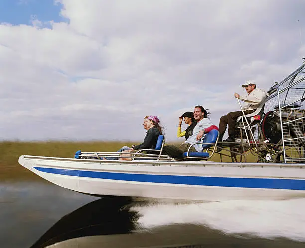 Photo of Driver and four passengers on airboat, side view