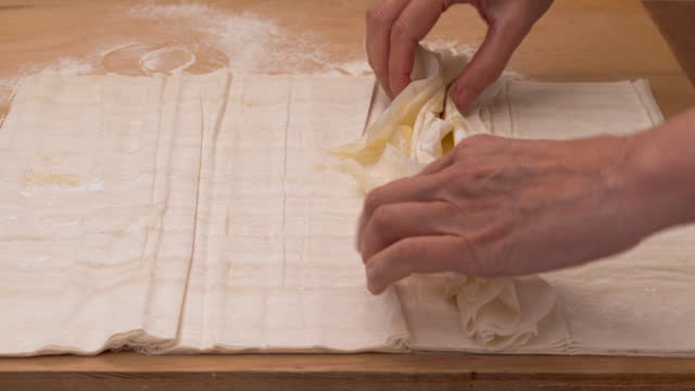 Chef folding buttered layers of phyllo dough into rolls