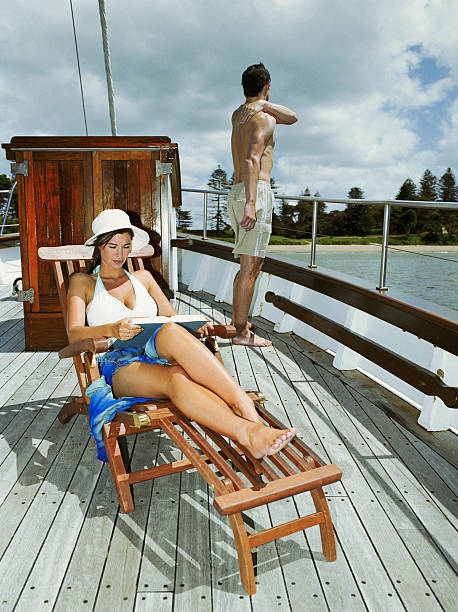 여자 on 돛단배 앉아 라운지 의자, 독서모드, man in 등근육 - outdoor chair beach chair sarong 뉴스 사진 이미지