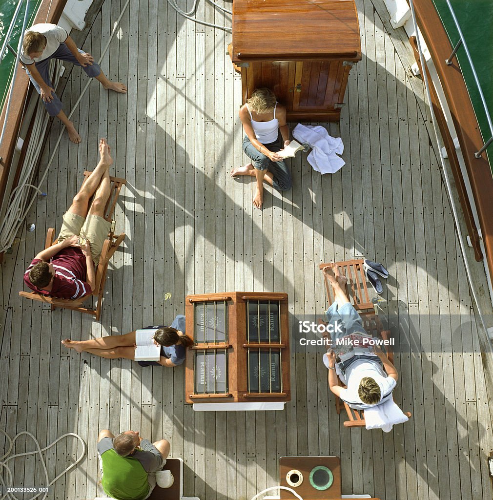 Group of friends reading on deck of sailboat, overhead view Hauraki Gulf, New Zealand Boat Deck Stock Photo