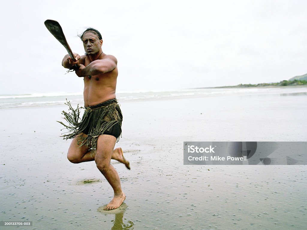 Maori man performing Haka Powhiri on beach Haka Pohiri is a welcome Dance. Muriwai Beach, North Island, New Zealand. Māori People Stock Photo