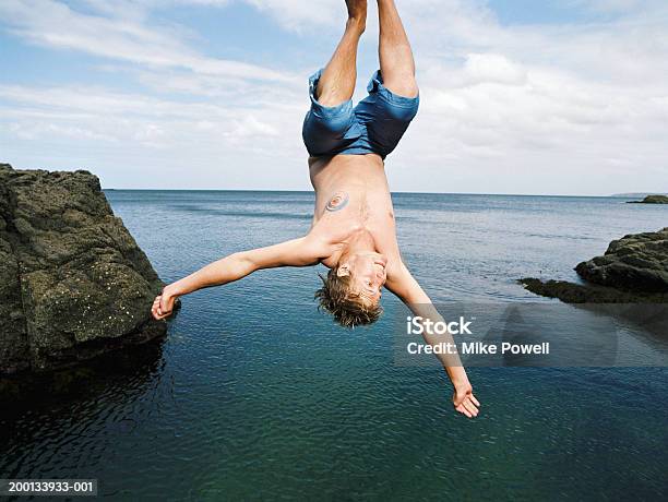 Young Man Doing Somersault Into Water Below Stock Photo - Download Image Now - Diving Into Water, Upside Down, Sea
