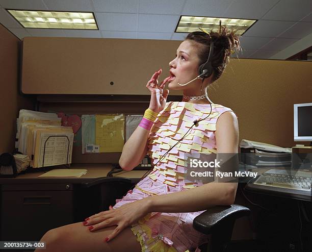 Woman In Dress Made Of Office Supplies At Desk Wearing Headset Stock Photo - Download Image Now