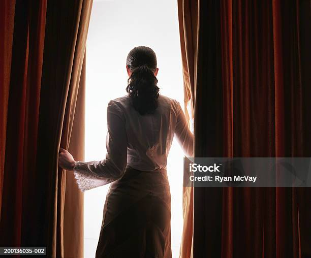 Young Woman Looking Through Red Curtains Rear View Stock Photo - Download Image Now