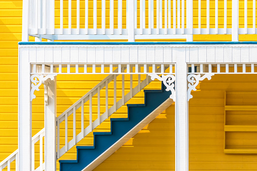 Yellow and blue wooden house in the Magdalen Islands, Canada. These traditional houses are painted in bright tones with decorate carved wood details. Abstract closeup.