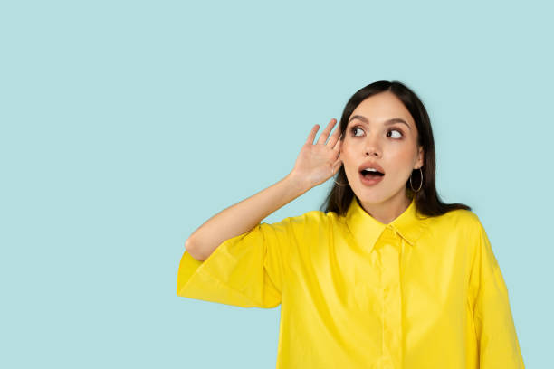istock Curious young woman eavesdropping, holding hand next to ear 2001377426