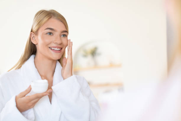 istock Attractive blonde young lady applies moisturizer in modern bathroom 2001377461