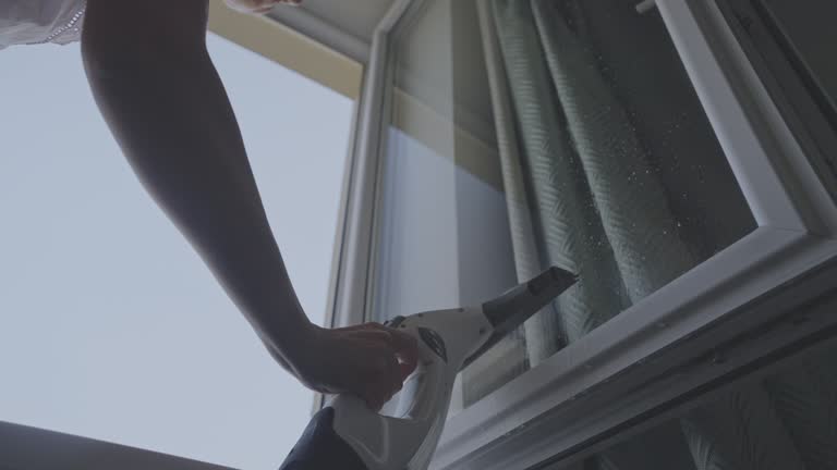 Housewife with special cleaning tool in hand washing wet window