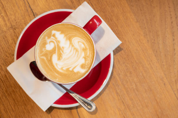A cup of hot latte coffee on wooden table.