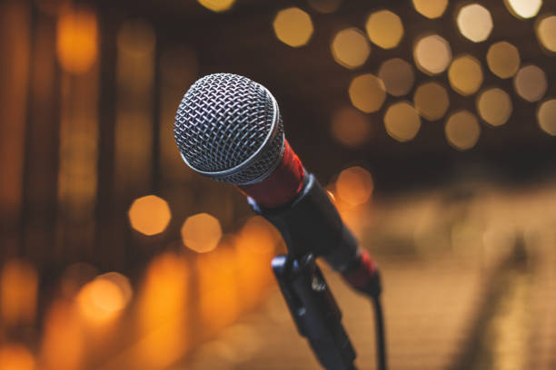istock Concert Backstage - Microphone On The Theater Stage Before The Show With Empty Seats And Blurred Lights 2001433583