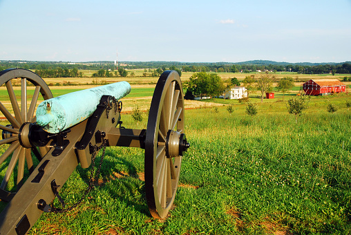 An American Civil War era cannon Is perched on a hill, overlooking farmland at Gettysburg National Military Park, part of the historic battlefield